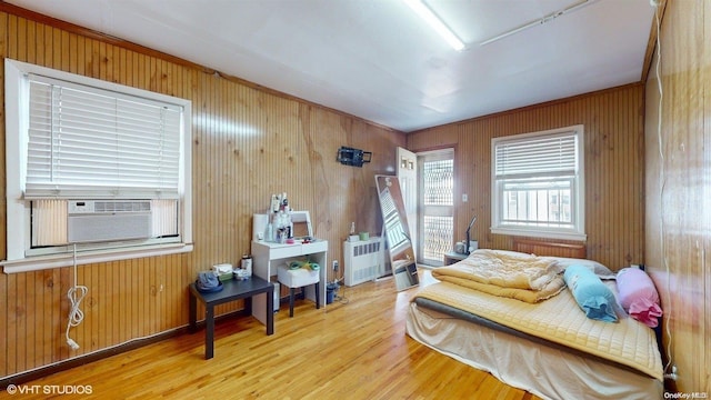 bedroom with wood-type flooring, radiator, cooling unit, and wood walls