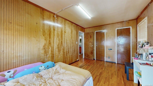 bedroom with a closet, wooden walls, hardwood / wood-style floors, and ornamental molding