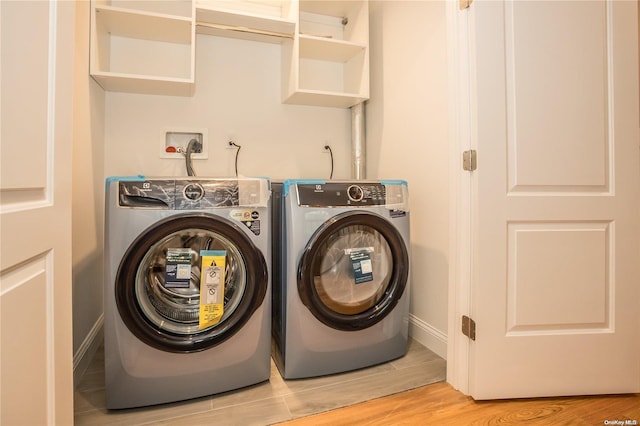 clothes washing area with washer and dryer and light hardwood / wood-style floors