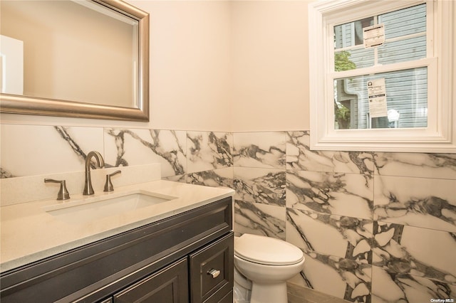 bathroom with vanity, toilet, and tile walls