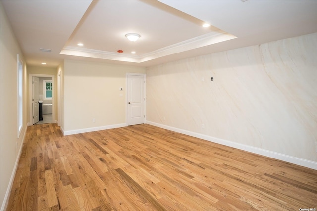 empty room featuring ornamental molding, light hardwood / wood-style flooring, and a tray ceiling