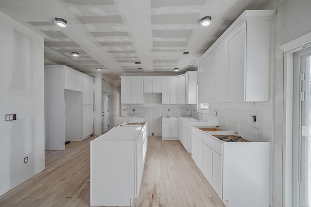 kitchen featuring light wood-style flooring, white cabinets, washer / dryer, coffered ceiling, and beamed ceiling