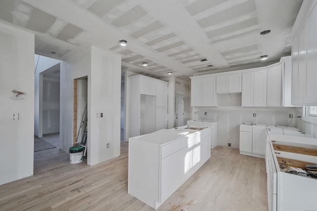 kitchen featuring light wood-style floors, white cabinetry, and beam ceiling