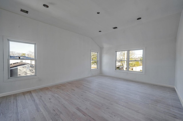 empty room with lofted ceiling, visible vents, baseboards, and wood finished floors