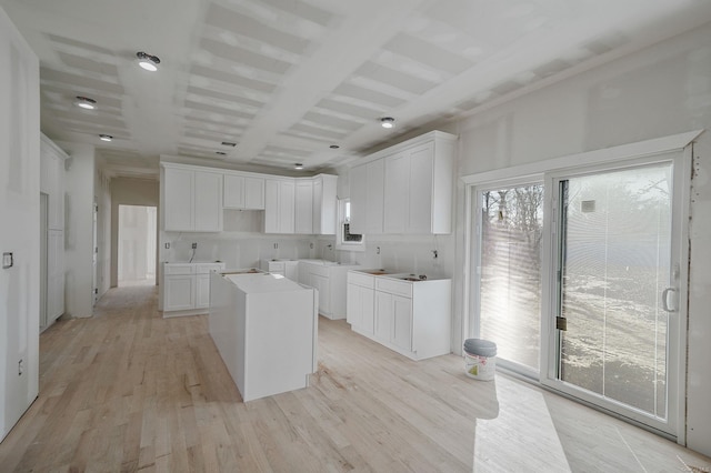 kitchen with light wood finished floors, a kitchen island, and white cabinetry