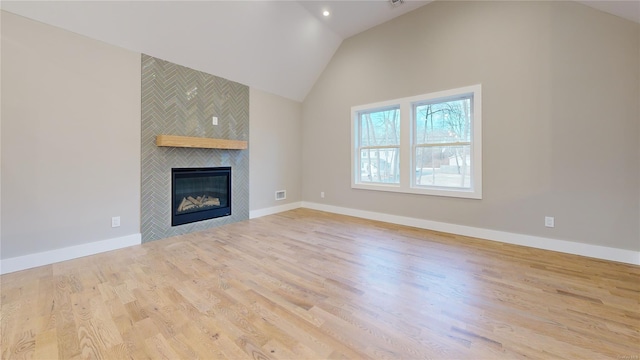 unfurnished living room with a tiled fireplace, high vaulted ceiling, and light hardwood / wood-style flooring