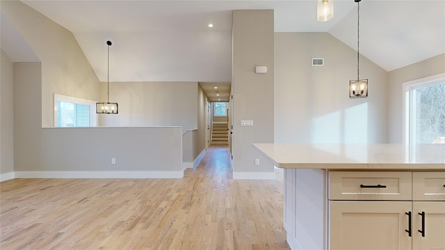 kitchen with pendant lighting, white cabinetry, lofted ceiling, and light wood-type flooring