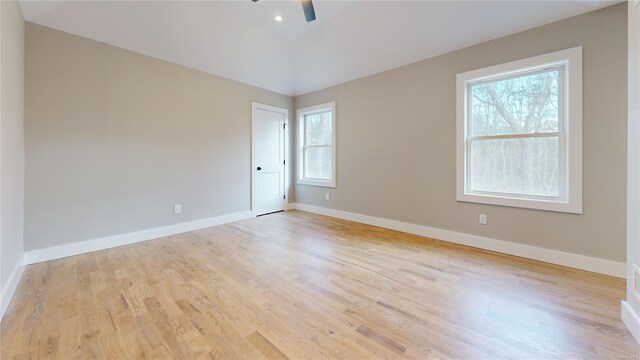 empty room with ceiling fan, lofted ceiling, and light wood-type flooring