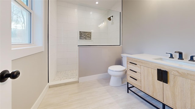 bathroom featuring toilet, vanity, and a tile shower