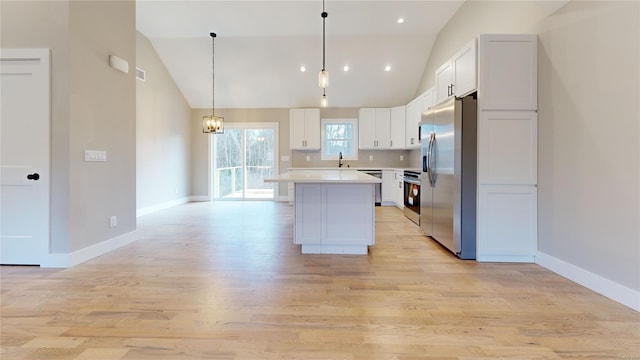 kitchen featuring a kitchen island, appliances with stainless steel finishes, pendant lighting, white cabinets, and light hardwood / wood-style floors