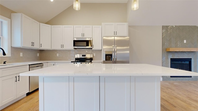 kitchen featuring white cabinetry, hanging light fixtures, light stone countertops, and appliances with stainless steel finishes