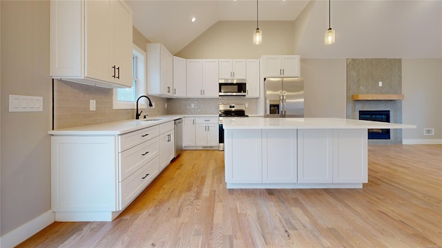 kitchen featuring white cabinetry, decorative light fixtures, stainless steel appliances, and a kitchen island