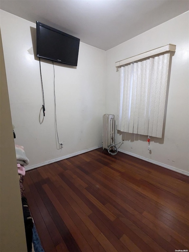 unfurnished bedroom featuring radiator heating unit and dark wood-type flooring