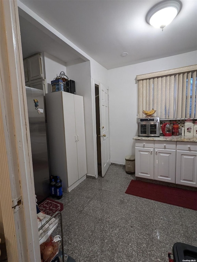 kitchen with white cabinetry and stainless steel refrigerator