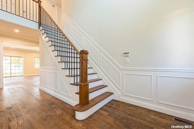 staircase with hardwood / wood-style floors and ornamental molding