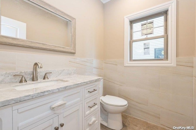 bathroom featuring tile patterned floors, vanity, tile walls, and toilet