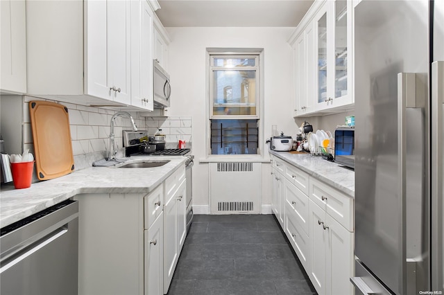 kitchen featuring light stone countertops, appliances with stainless steel finishes, sink, white cabinets, and radiator heating unit