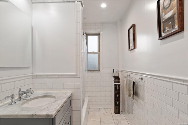 bathroom with vanity, a bathtub, and tile walls