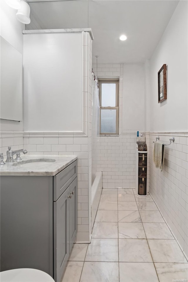 bathroom with vanity, tile walls, and shower / tub combo