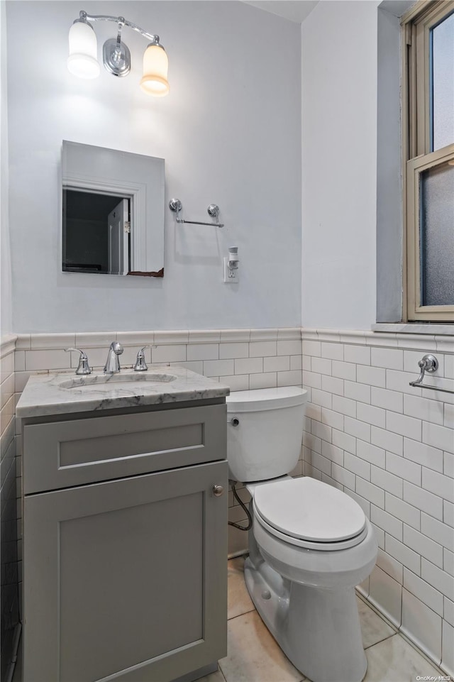 bathroom with tile patterned flooring, vanity, tile walls, and toilet