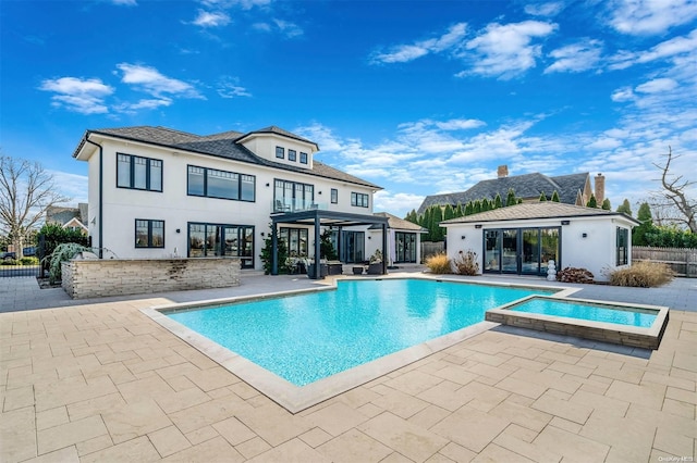 rear view of property with a patio area and a swimming pool with hot tub