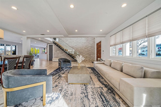 living room featuring beamed ceiling, light wood-type flooring, and plenty of natural light