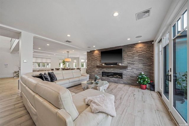 living room with a stone fireplace and light wood-type flooring