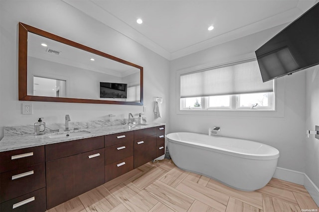 bathroom with a bathing tub, vanity, and ornamental molding