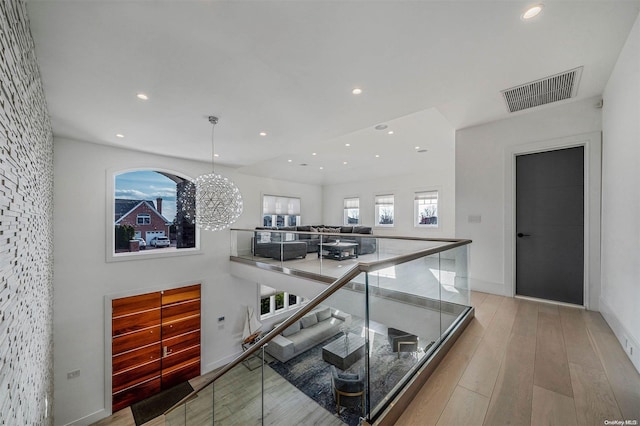 hallway featuring light hardwood / wood-style floors and an inviting chandelier