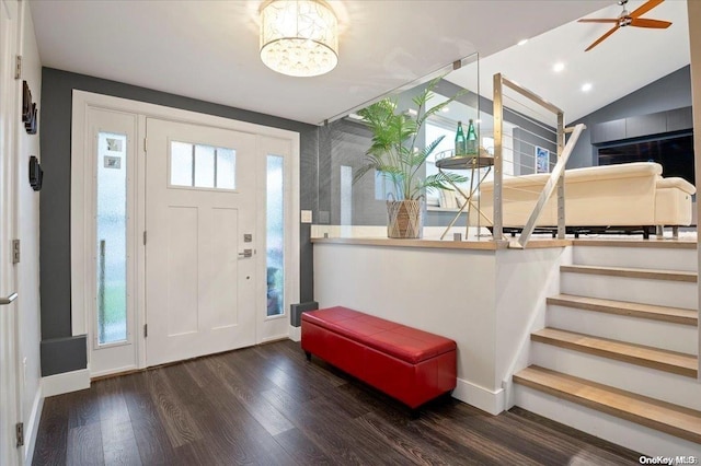 entrance foyer with ceiling fan with notable chandelier, dark hardwood / wood-style flooring, and vaulted ceiling