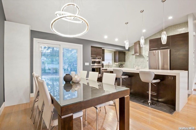 dining space featuring light hardwood / wood-style floors and lofted ceiling