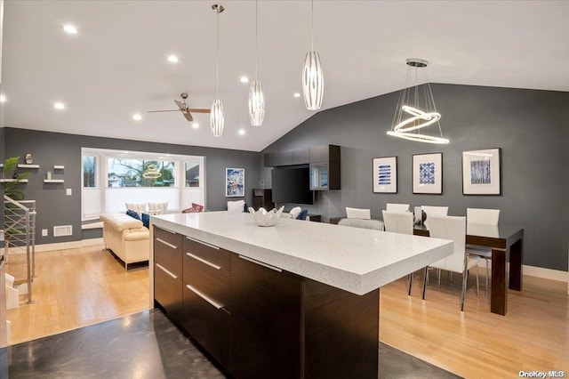 kitchen featuring dark brown cabinetry, vaulted ceiling, ceiling fan, a center island, and hanging light fixtures