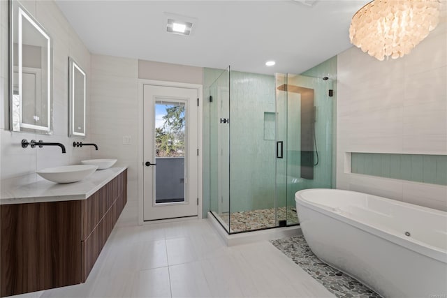 bathroom featuring tile patterned flooring, a chandelier, shower with separate bathtub, vanity, and tile walls