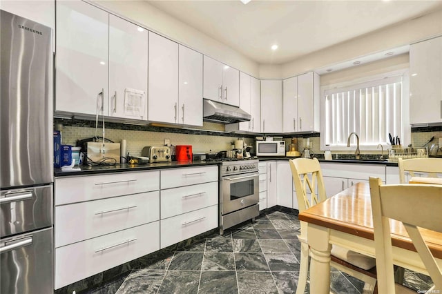 kitchen featuring appliances with stainless steel finishes, backsplash, white cabinetry, and sink