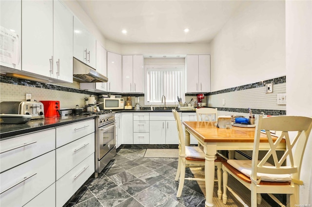 kitchen featuring white cabinetry, sink, high end range, and backsplash