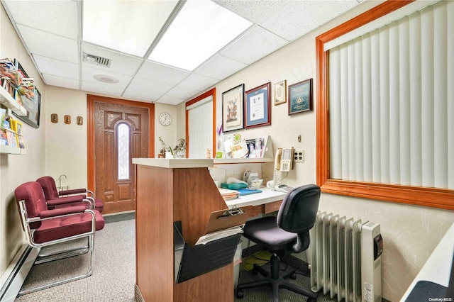 office area featuring carpet flooring, radiator, a drop ceiling, and a baseboard radiator