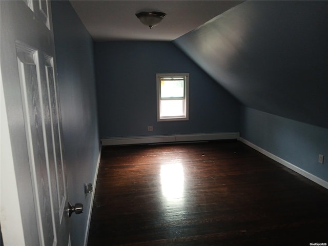 additional living space featuring dark hardwood / wood-style flooring, baseboard heating, and vaulted ceiling