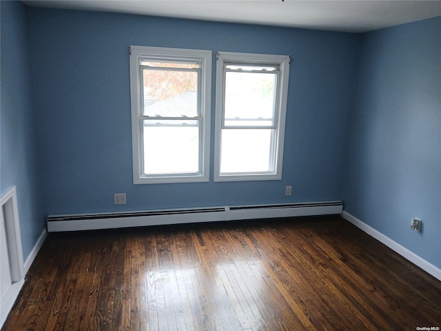 spare room with a baseboard radiator and dark wood-type flooring