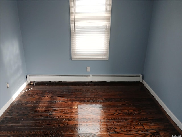 spare room with a baseboard radiator, a wealth of natural light, and dark wood-type flooring