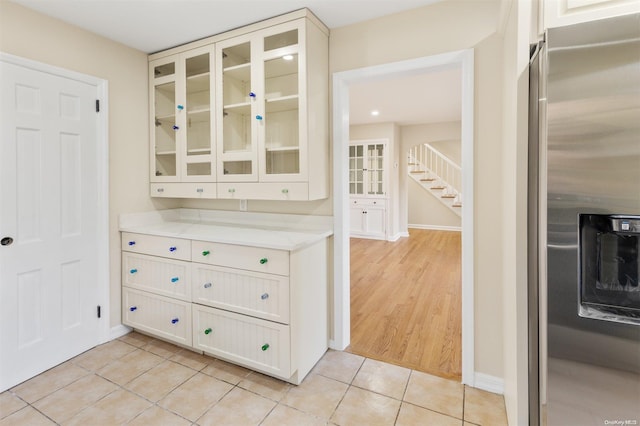 kitchen with light tile patterned floors, white cabinets, and stainless steel refrigerator with ice dispenser