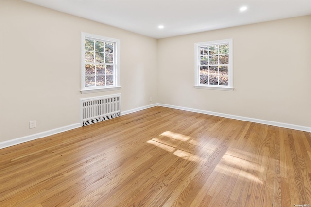 spare room featuring light wood-type flooring and radiator