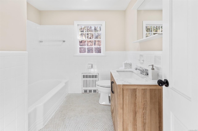 bathroom with vanity, tile walls, radiator heating unit, toilet, and a tub