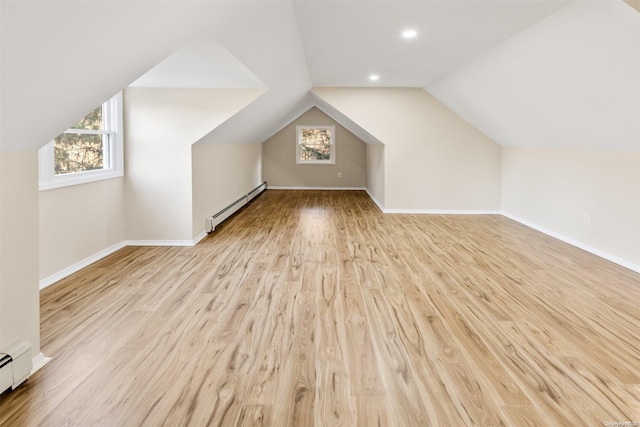 additional living space featuring light wood-type flooring, baseboard heating, and lofted ceiling