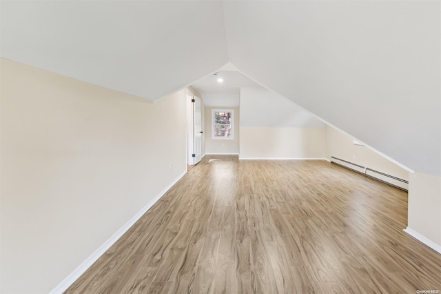 bonus room featuring lofted ceiling, light hardwood / wood-style flooring, and a baseboard heating unit