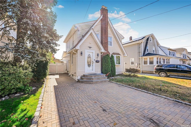 view of front of home featuring entry steps, a chimney, and fence