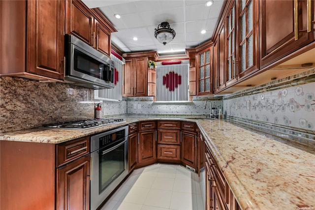 kitchen featuring light stone countertops, sink, decorative backsplash, light tile patterned floors, and appliances with stainless steel finishes