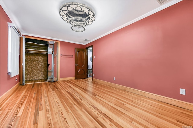 unfurnished bedroom featuring hardwood / wood-style flooring, crown molding, and a closet