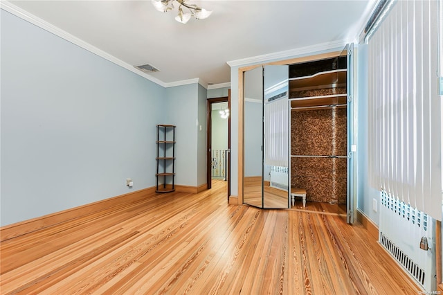 unfurnished bedroom with wood-type flooring, crown molding, radiator, and a closet