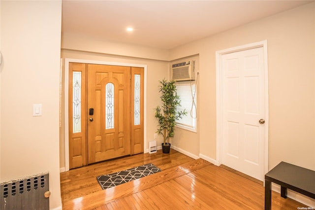 entrance foyer featuring hardwood / wood-style floors, radiator, and a wall mounted AC