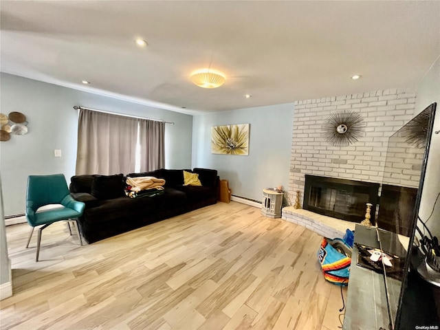 living room featuring light hardwood / wood-style floors, a baseboard heating unit, and a brick fireplace